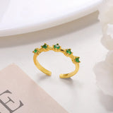 Gold ring with green gemstones on a light background