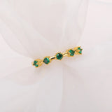 Gold ring with green gemstones on a white background