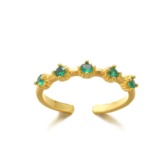 Gold ring with emerald stones on a white background