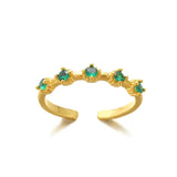Gold ring with emerald stones on a white background
